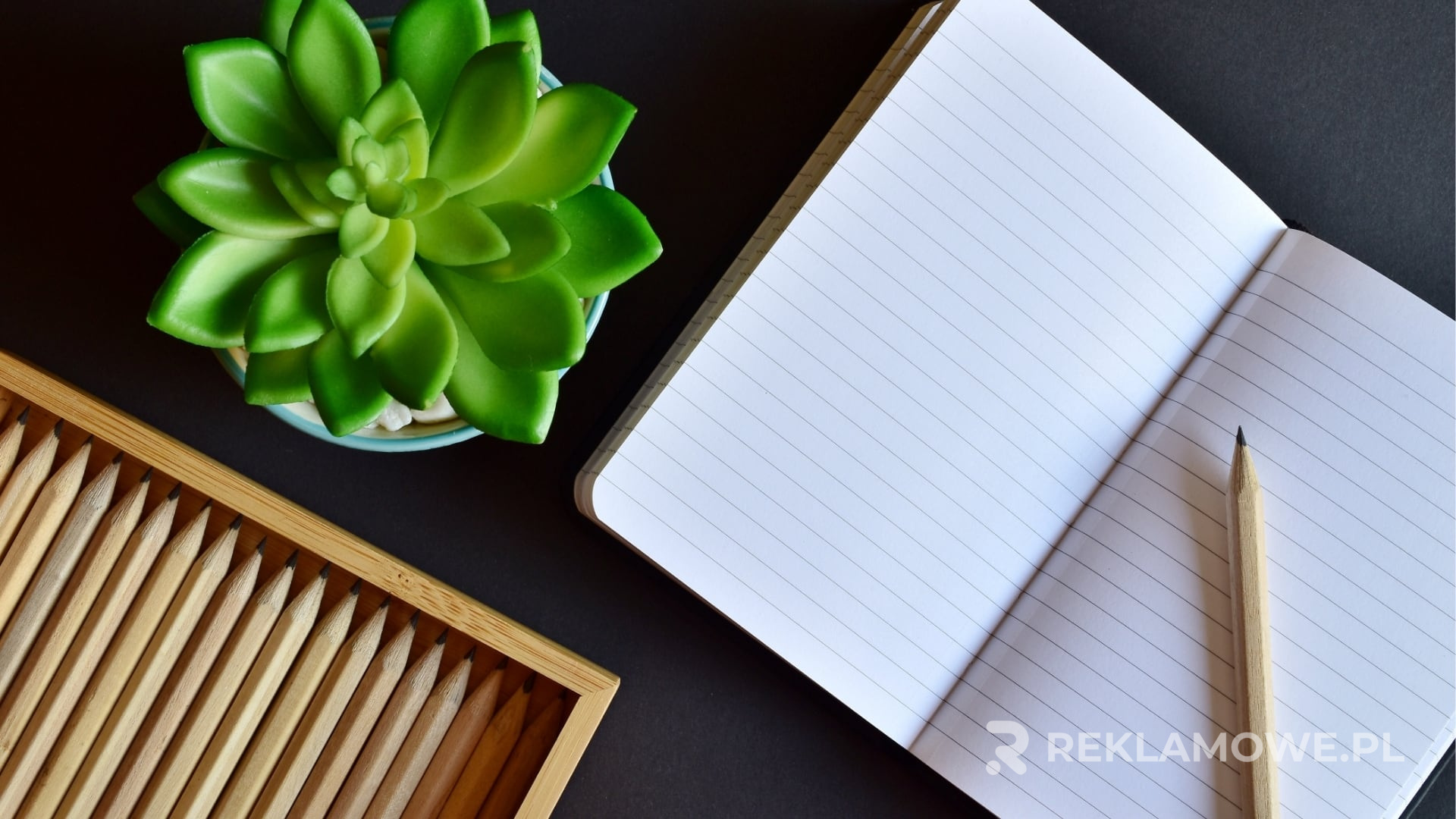 Notatnik reklamowy na biurku obok laptopa i komórki