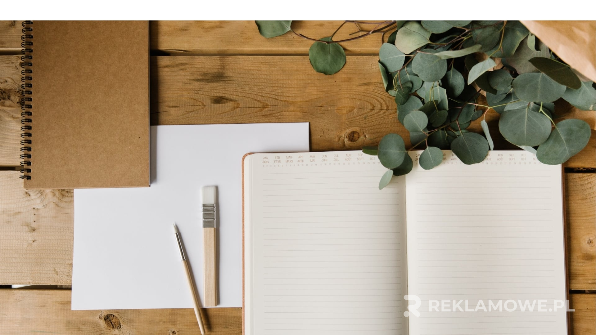 Notatnik reklamowy na biurku z telefonem komórkowym i laptopem